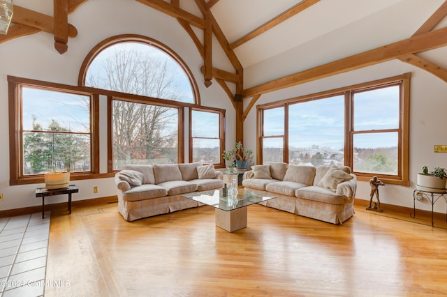 living room featuring beamed ceiling, high vaulted ceiling, light wood-type flooring, and a wealth of natural light