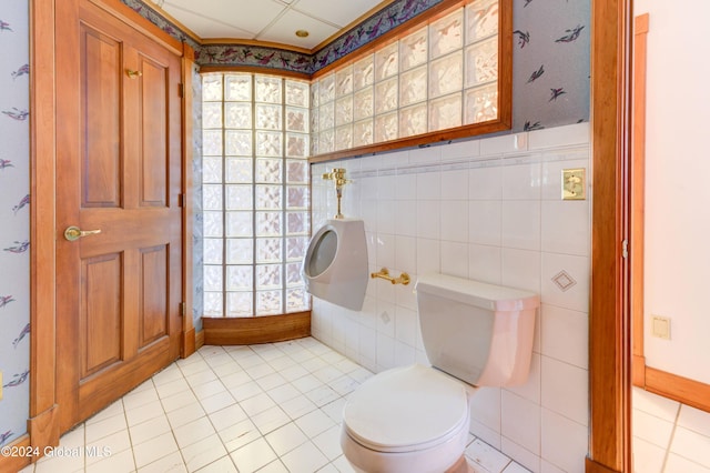 bathroom with tile patterned floors, toilet, and tile walls