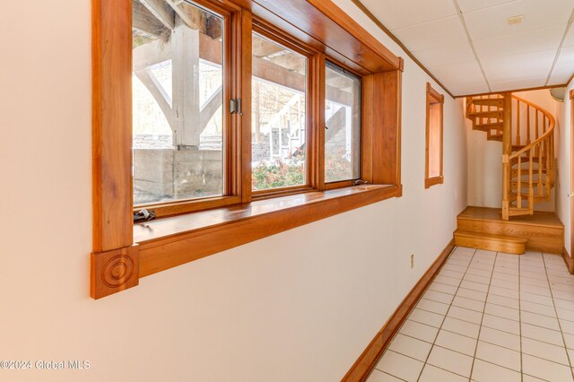 hall with a drop ceiling and light tile patterned flooring