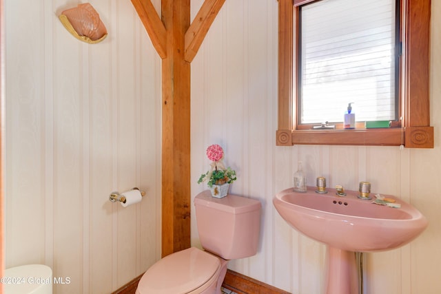 bathroom featuring wooden walls and toilet