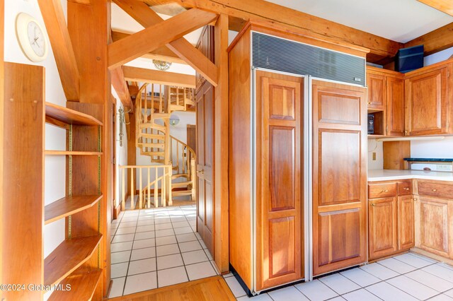 kitchen featuring paneled fridge, light tile patterned floors, and beamed ceiling