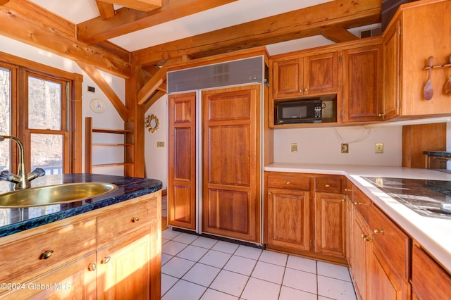 kitchen with beamed ceiling, light tile patterned flooring, paneled refrigerator, and sink