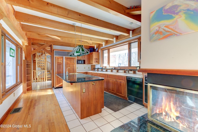 kitchen featuring light wood-type flooring, black appliances, pendant lighting, beamed ceiling, and a center island