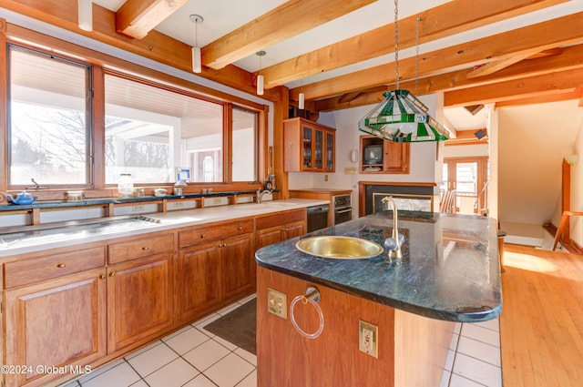 kitchen featuring a center island with sink, pendant lighting, beamed ceiling, and a breakfast bar area