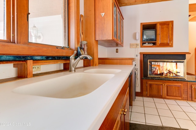 kitchen featuring a multi sided fireplace, light tile patterned floors, and sink