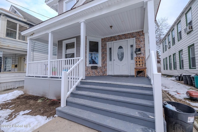 snow covered property entrance featuring a porch