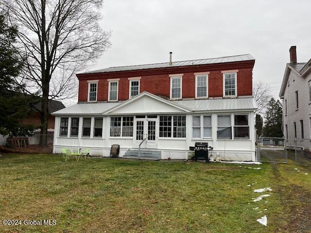 back of property with a sunroom and a yard