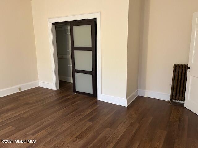 unfurnished room featuring radiator heating unit and dark wood-type flooring