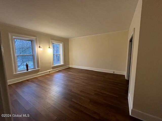 spare room featuring dark hardwood / wood-style flooring and ornamental molding