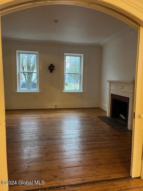 unfurnished living room featuring hardwood / wood-style floors and ornamental molding