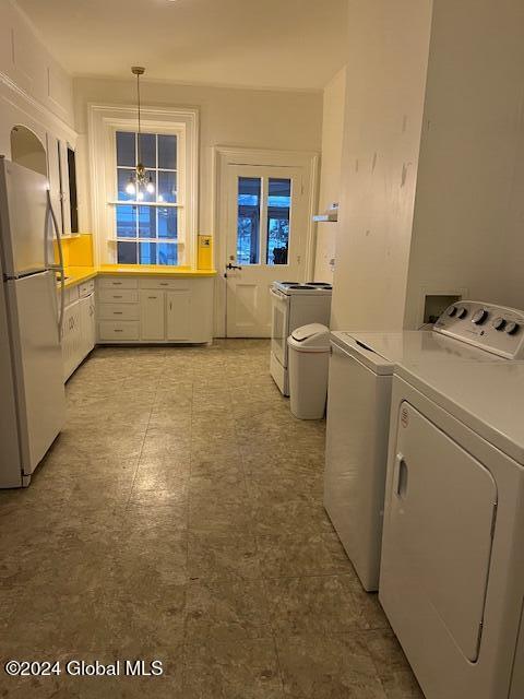 clothes washing area with washer and dryer and a chandelier