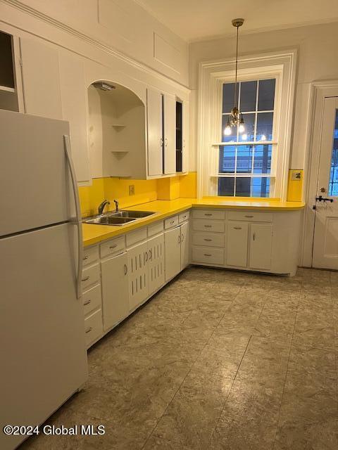 kitchen featuring pendant lighting, sink, a notable chandelier, white fridge, and white cabinetry