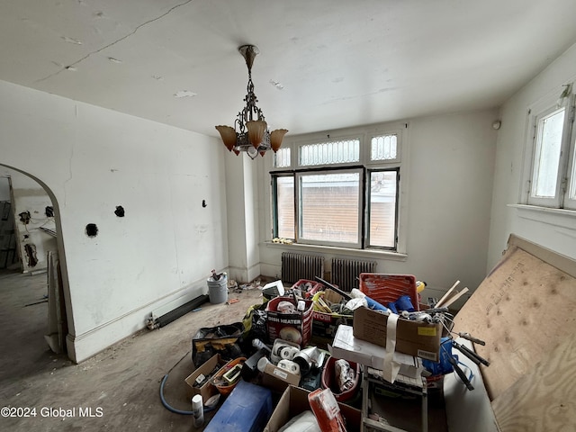 misc room with concrete floors, radiator heating unit, and a chandelier