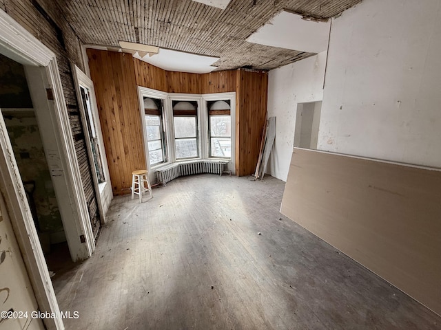 miscellaneous room with wood walls, radiator heating unit, and wood-type flooring