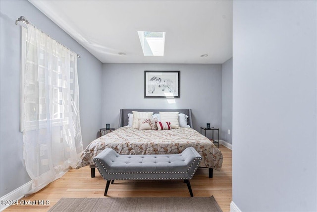 bedroom with a skylight and light hardwood / wood-style flooring