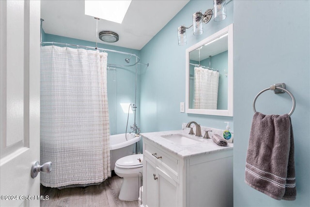 full bathroom with vanity, a skylight, hardwood / wood-style flooring, toilet, and shower / bath combo with shower curtain