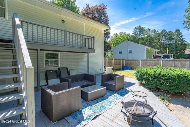 view of patio / terrace with a balcony, a wooden deck, and an outdoor living space with a fire pit