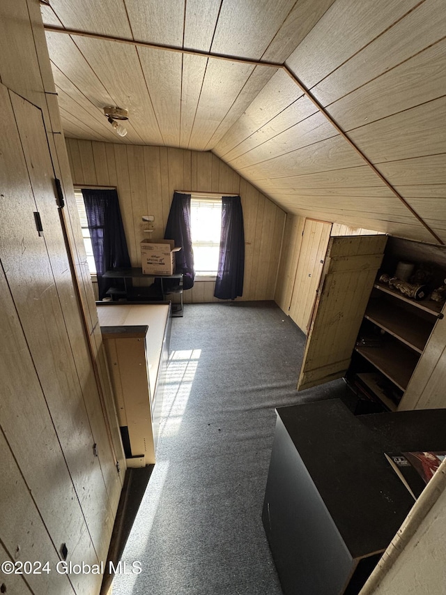 additional living space with wood walls, carpet, and vaulted ceiling