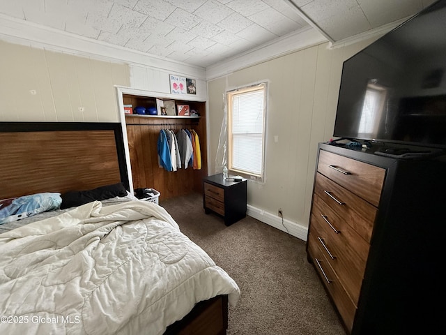 bedroom with baseboards, ornamental molding, dark carpet, and a closet