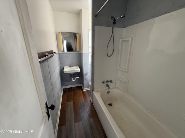 bathroom featuring hardwood / wood-style floors, washtub / shower combination, and sink