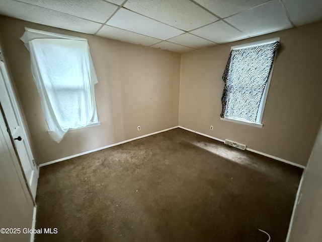 unfurnished room with a paneled ceiling, baseboards, visible vents, and plenty of natural light
