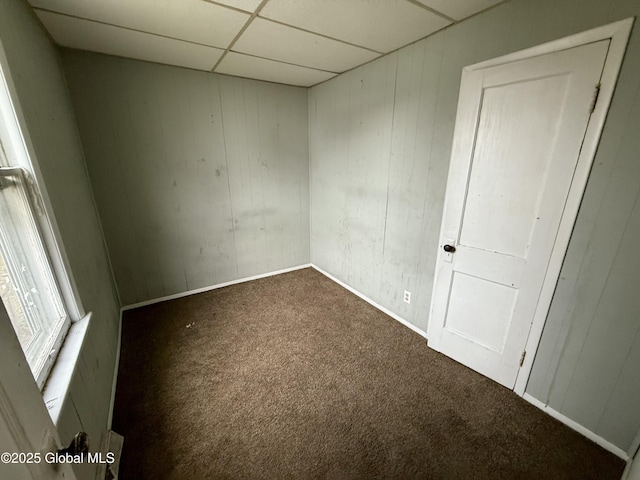carpeted empty room with baseboards and a drop ceiling