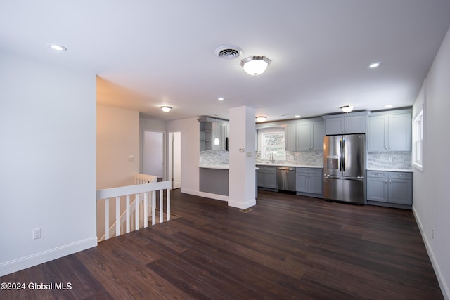 kitchen featuring tasteful backsplash, gray cabinets, dark hardwood / wood-style flooring, and stainless steel appliances