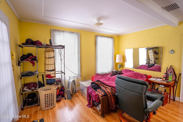 bedroom with beam ceiling, crown molding, and wood-type flooring