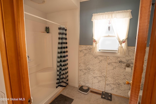 bathroom with curtained shower and tile walls