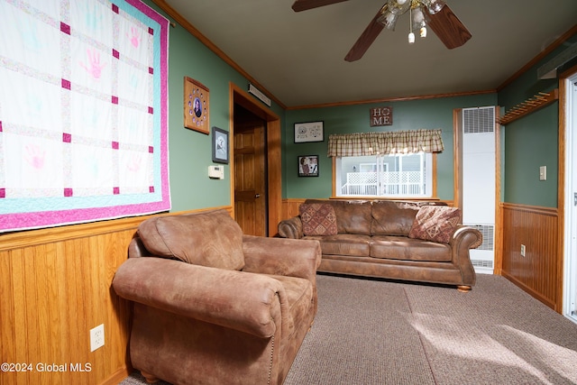 carpeted living room featuring wooden walls, ceiling fan, and crown molding