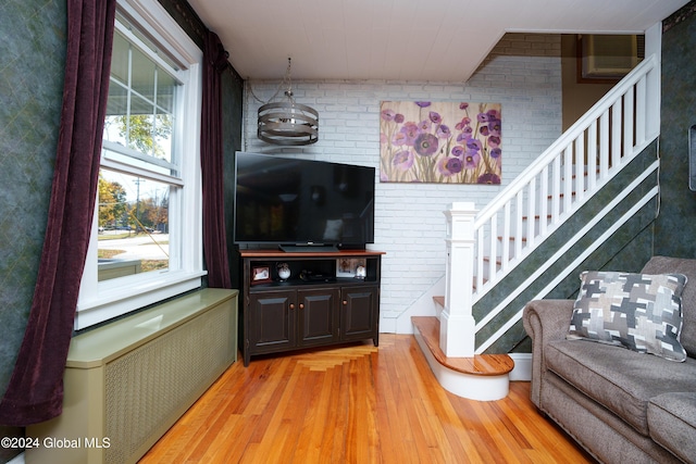 living room featuring radiator, brick wall, and light hardwood / wood-style flooring