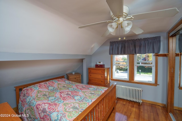 bedroom with radiator heating unit, vaulted ceiling, ceiling fan, and hardwood / wood-style floors