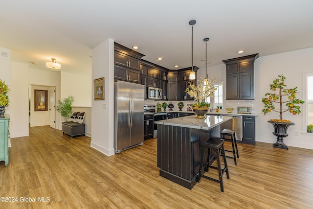 kitchen with pendant lighting, a kitchen island, stainless steel appliances, and light hardwood / wood-style floors