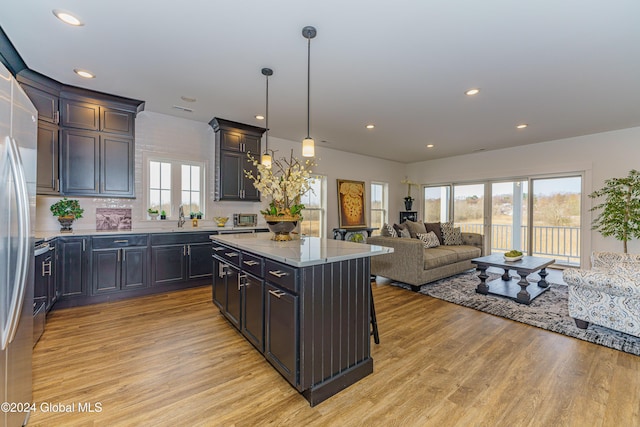 kitchen featuring sink, light hardwood / wood-style flooring, pendant lighting, a breakfast bar area, and a kitchen island