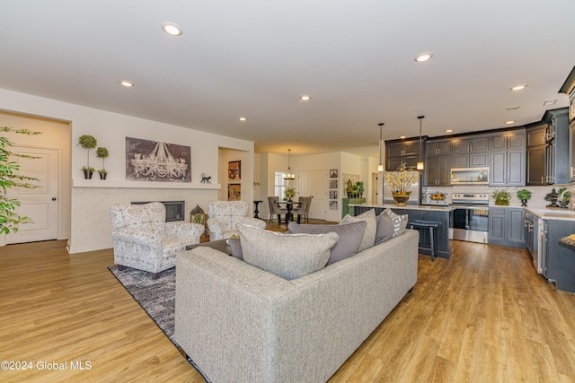 living room featuring sink, light hardwood / wood-style floors, and an inviting chandelier