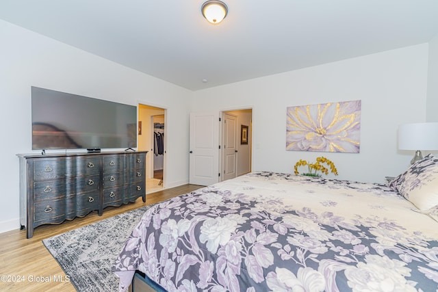 bedroom featuring light wood-type flooring, a walk in closet, and a closet