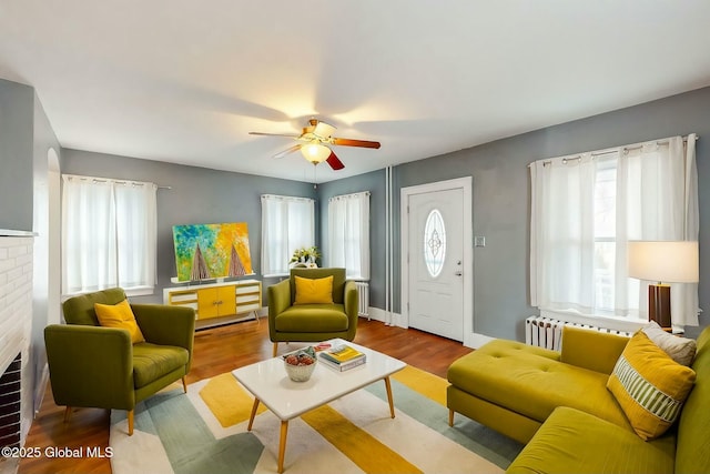 living room featuring light hardwood / wood-style floors, a brick fireplace, a wealth of natural light, and ceiling fan