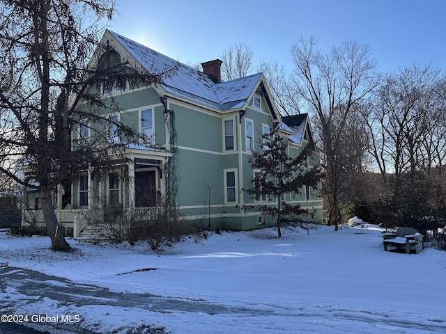 view of snow covered exterior featuring a chimney