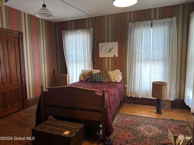 bedroom with wood finished floors and wallpapered walls