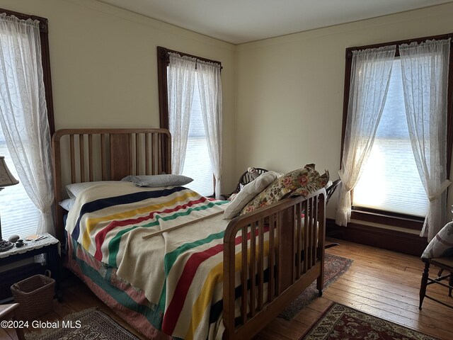 bedroom with ornamental molding and hardwood / wood-style floors