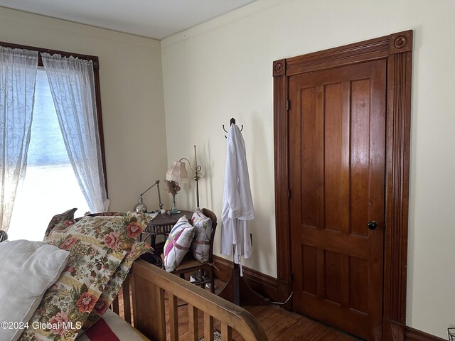 bedroom featuring wood finished floors and ornamental molding