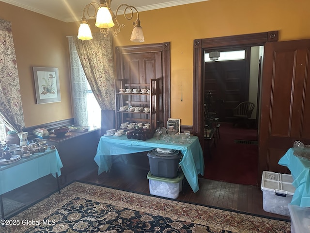 dining room featuring crown molding, hardwood / wood-style flooring, and a notable chandelier