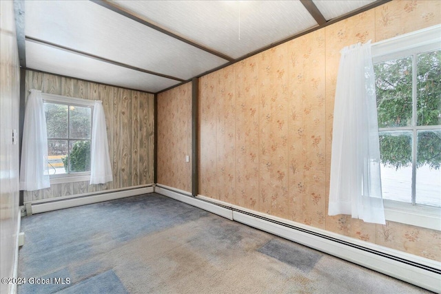 carpeted empty room featuring baseboard heating and wooden walls