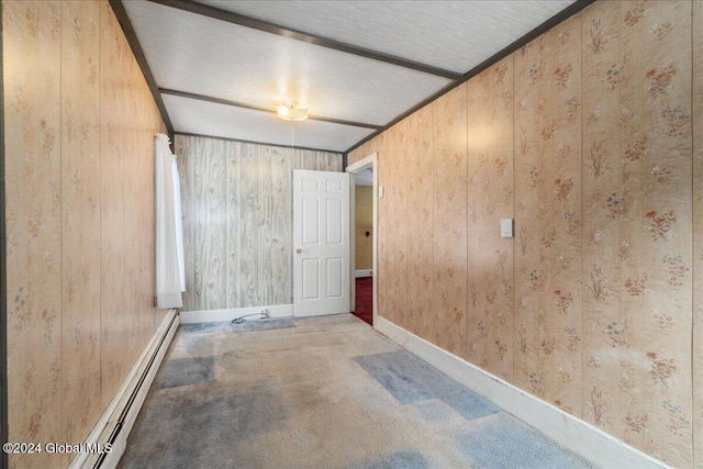 carpeted spare room with baseboard heating and wood walls