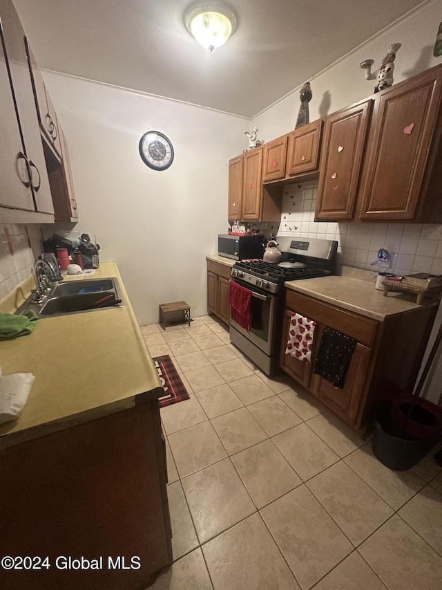 kitchen with backsplash, sink, light tile patterned flooring, and appliances with stainless steel finishes