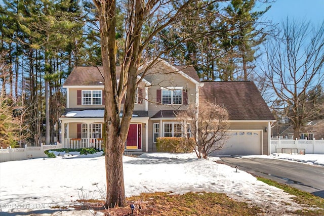 traditional-style home with a porch, driveway, a garage, and fence