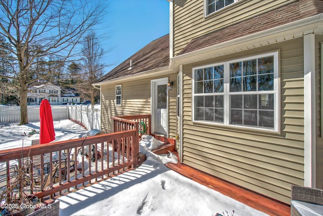 snow covered deck featuring entry steps and fence