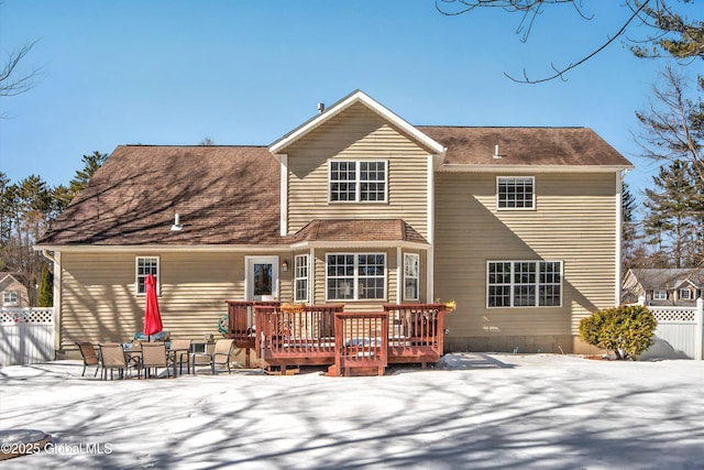 snow covered house with fence and a wooden deck