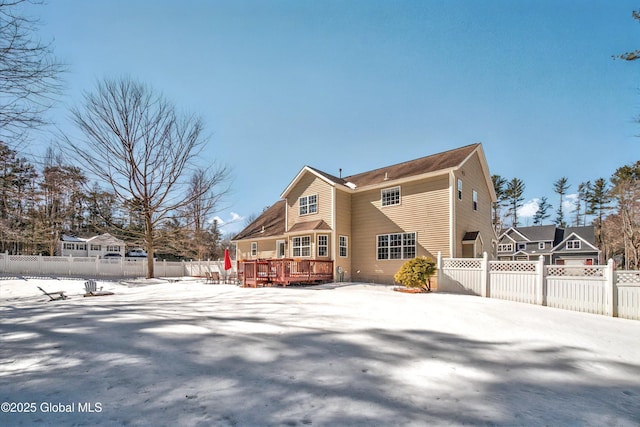 snow covered rear of property featuring a wooden deck and a fenced backyard