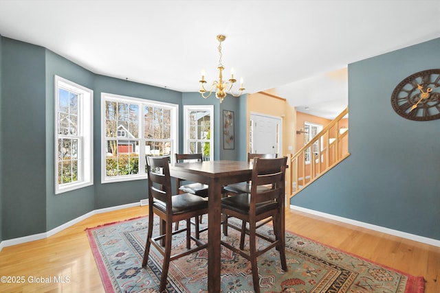 dining room featuring light wood finished floors, stairway, a chandelier, and baseboards